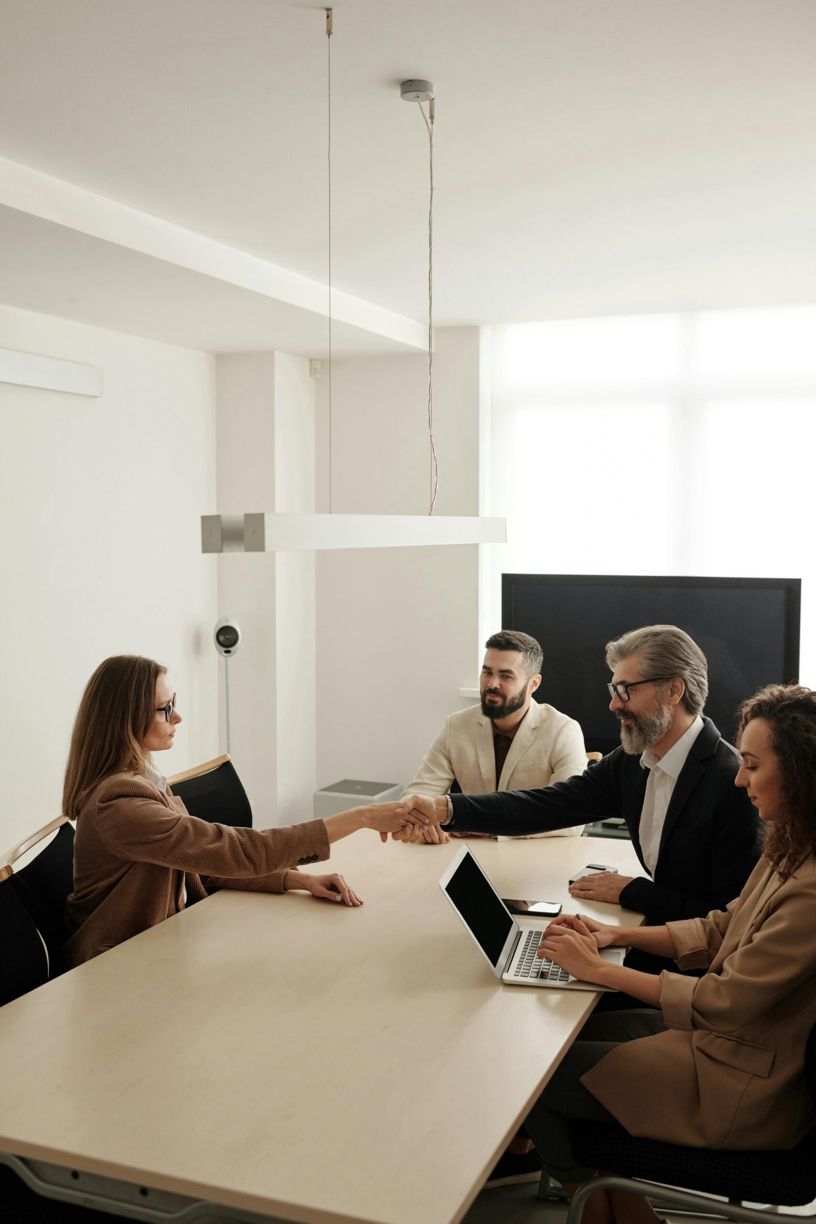 A group of happy, diverse colleagues celebrating teamwork and cooperation with a group high five indoors.